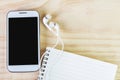 Smart phone and open notebook on wooden table Royalty Free Stock Photo