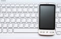 Smart phone over white keyboard