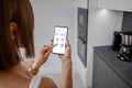 Controlling smart devices with phone on the kitchen Royalty Free Stock Photo