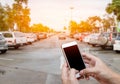 Smart phone showing blank screen in man hand with blur cars park