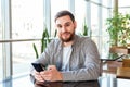 Smart phone texting. Attractive bearded caucasian businessman using smartphone while sitting in office. Businessman using mobile Royalty Free Stock Photo