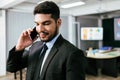 Smart and positive businessman calling and talking on smart phone alone in the office. Professional making business calls. Royalty Free Stock Photo