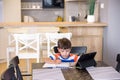 Smart preteen schoolboy doing his homework with digital tablet at home. Child using gadgets on his kitchen to study. Modern