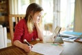 Smart schoolgirl doing her homework with digital tablet at home. Child using gadgets to study. Education and learning for kids. Royalty Free Stock Photo