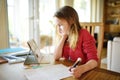 Smart preteen schoolgirl doing her homework with digital tablet at home. Child using gadgets to study Royalty Free Stock Photo