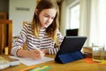 Smart preteen schoolgirl doing her homework with digital tablet at home. Education and distance learning for kids. Homeschooling Royalty Free Stock Photo