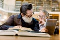 Smart pretty girl in eyeglasses and old man teacher having a lesson and discussion in vintage library. Girl holds Royalty Free Stock Photo
