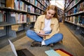 Girl student using laptop elearning sitting in university library on floor. Royalty Free Stock Photo