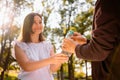 Smart pretty young woman in white blouse giving a bottle of water to a homeless poor man in old brown jacket, volunteer Royalty Free Stock Photo