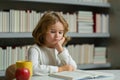 Smart pupil. Schoolboy reading book in library. Kids development, learn to read. Pupil reading books in a school library Royalty Free Stock Photo