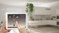 Smart remote home control system on a digital tablet. Device with app icons. Blurry interior of white kitchen in the background, a Royalty Free Stock Photo