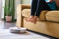 Smart Robot vacuum cleaner cleaning a living room with woman lifting her feet to create path way for the device