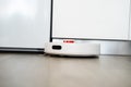 Smart robot vacuum cleaner navigating narrow space between kitchen cabinets Royalty Free Stock Photo