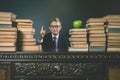 Smart school boy sitting at table with many books