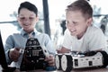 Smart schoolboys working with self automated robots in workshop