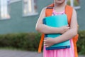 Smart schoolgirl outdoors.Little child holds notebooks