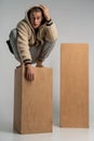 Smart serious young man in sportwear crouched on wood cube and posing Royalty Free Stock Photo