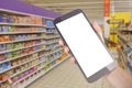 Hand holding tablet in supermarket corridor with goods shelves