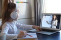 Smart small preschooler girl in headphones watch online lesson and communicate with teacher at home