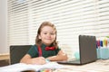 Smart smiling school pupil kid virtual distance learning online, watching remote digital class lesson, looking at laptop