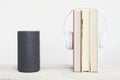 Smart speaker Amazon Alexa Echo device on the left next to some books and hearphones against a white background. Royalty Free Stock Photo