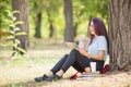 Smart student lady reading books and relaxing on a park background. Education concept. Copy space. Royalty Free Stock Photo