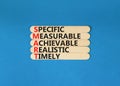 SMART symbol. Concept words SMART specific measurable achievable realistic timely on wooden stick. Beautiful blue background.