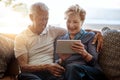 Smart technology just makes so much sense. a happy senior couple using a digital tablet together on the sofa at home.