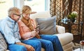 Smart technology just simplifies everything. a mature couple using a phone together at home on the sofa.