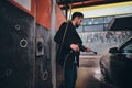 Smart trendy man in jeans and blaser is washing his own car at car washing station Royalty Free Stock Photo