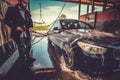 Smart trendy man in jeans and blaser is washing his own car at car washing station Royalty Free Stock Photo