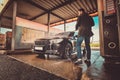 Smart trendy man in jeans and blaser is washing his own car at car washing station Royalty Free Stock Photo