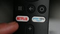 Smart Tv controller with Netflix and Prime video buttons. User is chosing Netflix and pushing Netflix button