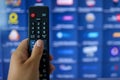 Smart tv and hand pressing remote control.Hand holding TV remote control with a television in the background. Close up Royalty Free Stock Photo