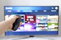 Smart TV remote controller in female hand on screen background Royalty Free Stock Photo