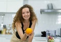 smart vegetarian woman smile, happy, show orange in hand, looking at camera in kitchen with copy space. beautiful caucasian woman