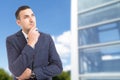 Smart visionary businessman looking up on glass building background.