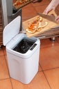 Smart waste basket. Electronic gadget for the home. Open cover. Female hands throw out trash. View from above. On brown tiles