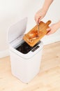 Smart waste basket. Electronic gadget for the home. Open cover. Female hands throw out trash. View from above. On brown tiles