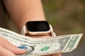 Smart watch on the girl`s hand took dollar bills on the street, money