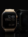 2 smart watches - Apple Watch 4, gold and black, on dark Royalty Free Stock Photo