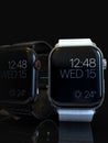 2 smart watches - Apple Watch 4, silver and black, on dark Royalty Free Stock Photo