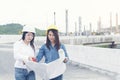 Smart woman engineer holding white hard hat on hand and look at refinery industry plant at industry factory center area.