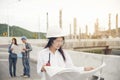 Smart woman engineer holding white hard hat on hand and look at refinery industry plant at industry factory center area.