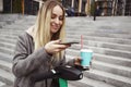 Smart woman using phone mobile app for rent e-scooter. She holding her smartphone and cup of coffee. Sharing electric Royalty Free Stock Photo