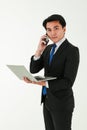 A smart young asian businessman or entrepreneur wearing formal black suit standing over white background, holding and looking at Royalty Free Stock Photo