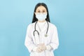 Smart young asian female doctor in lab coat with Medical face mask,white latex medical gloves and stethoscope against blue Royalty Free Stock Photo