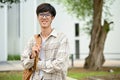 A smart young Asian male college student in glasses stands at the campus outdoor space Royalty Free Stock Photo