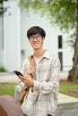 A smart young Asian male college student in glasses, stands at the campus outdoor space Royalty Free Stock Photo