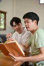 A smart young Asian male college student is explaining something in a book to his friend Royalty Free Stock Photo